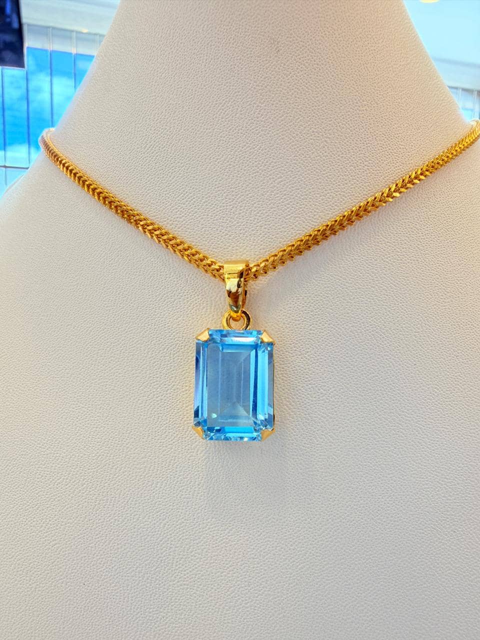 Gold pendant set with a blue topaz on a gold chain