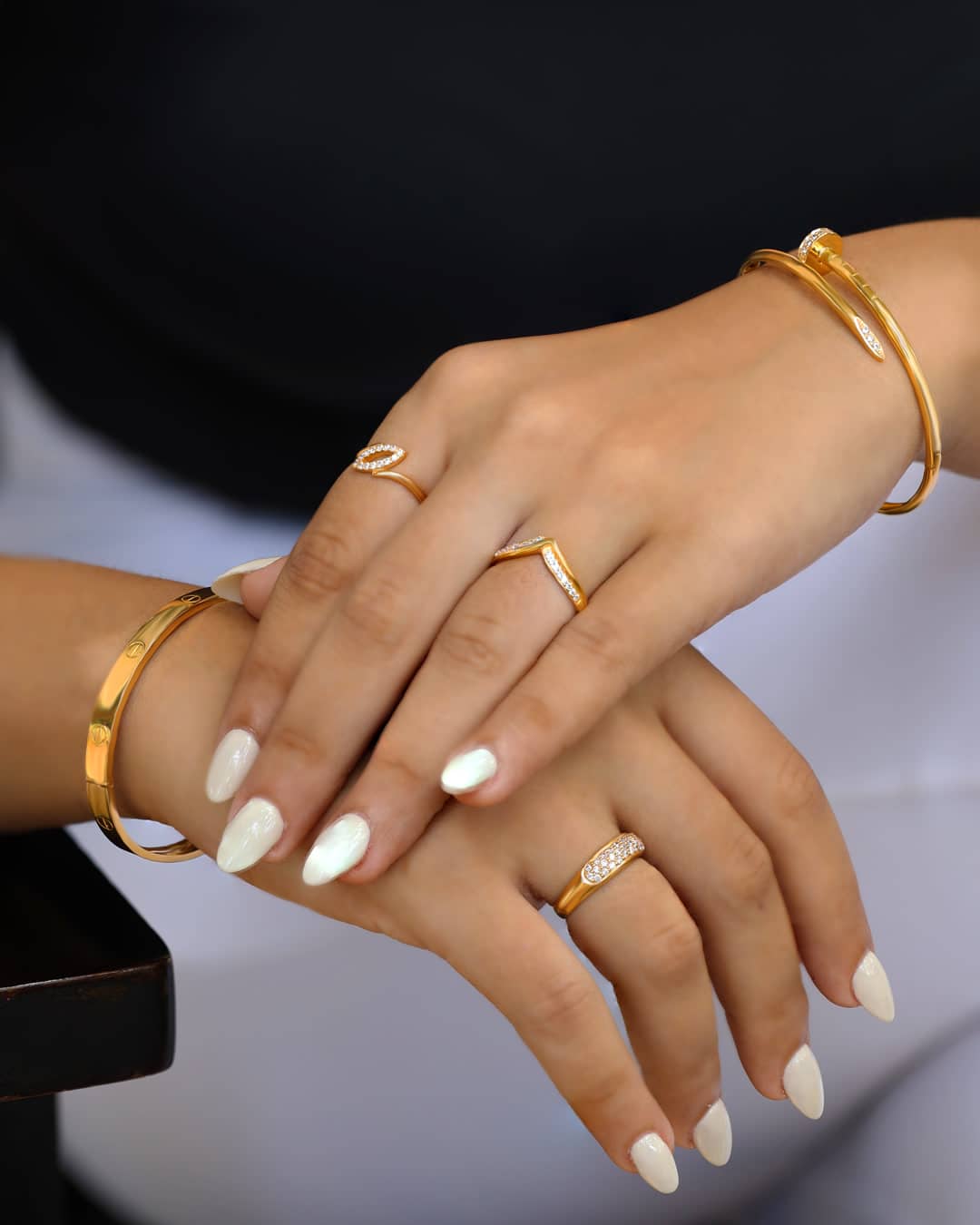 Gold rings and bangle bracelets worn on crossed hands