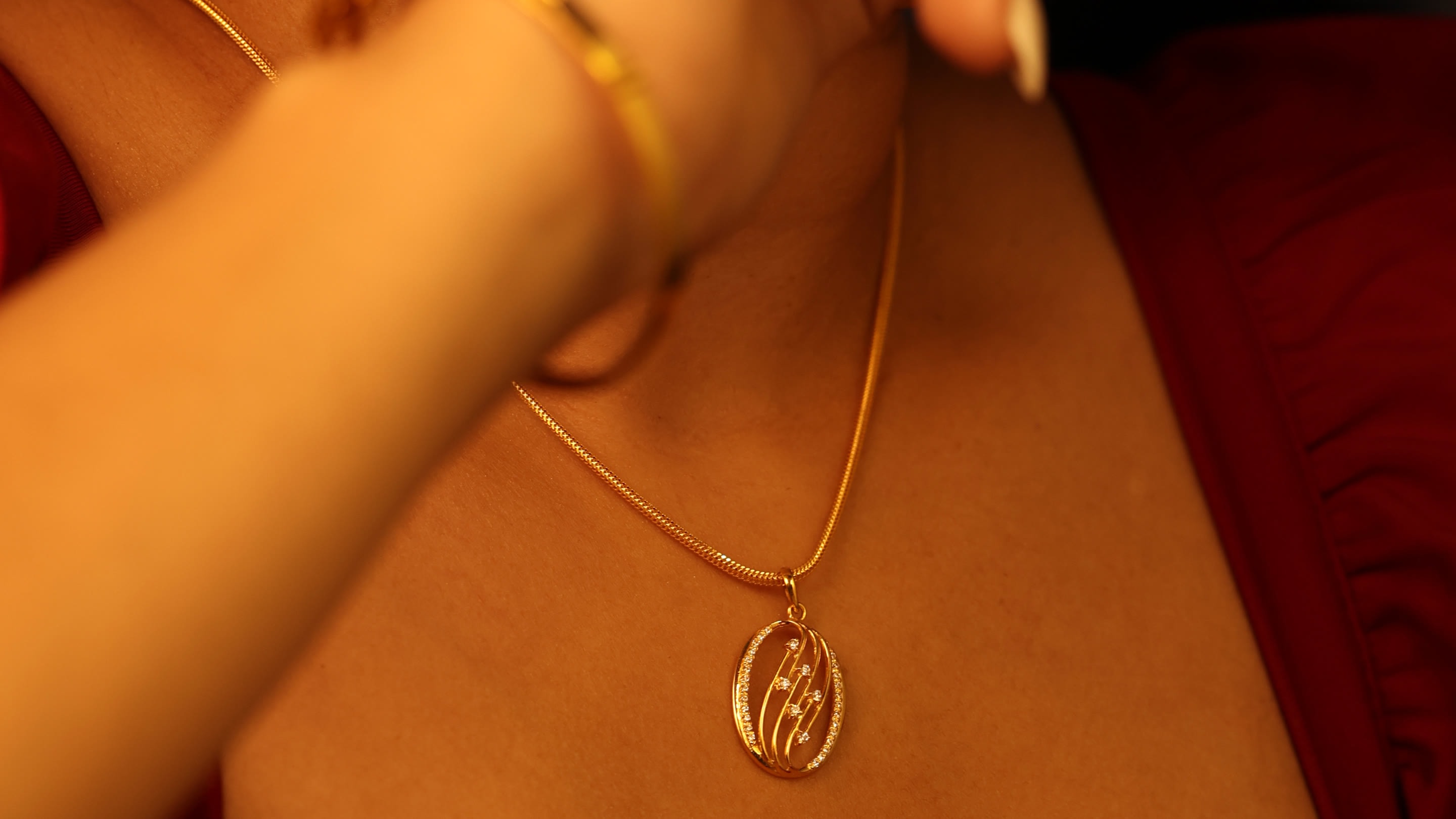 Oval gold pendant with sparkling stones on a fine gold chain